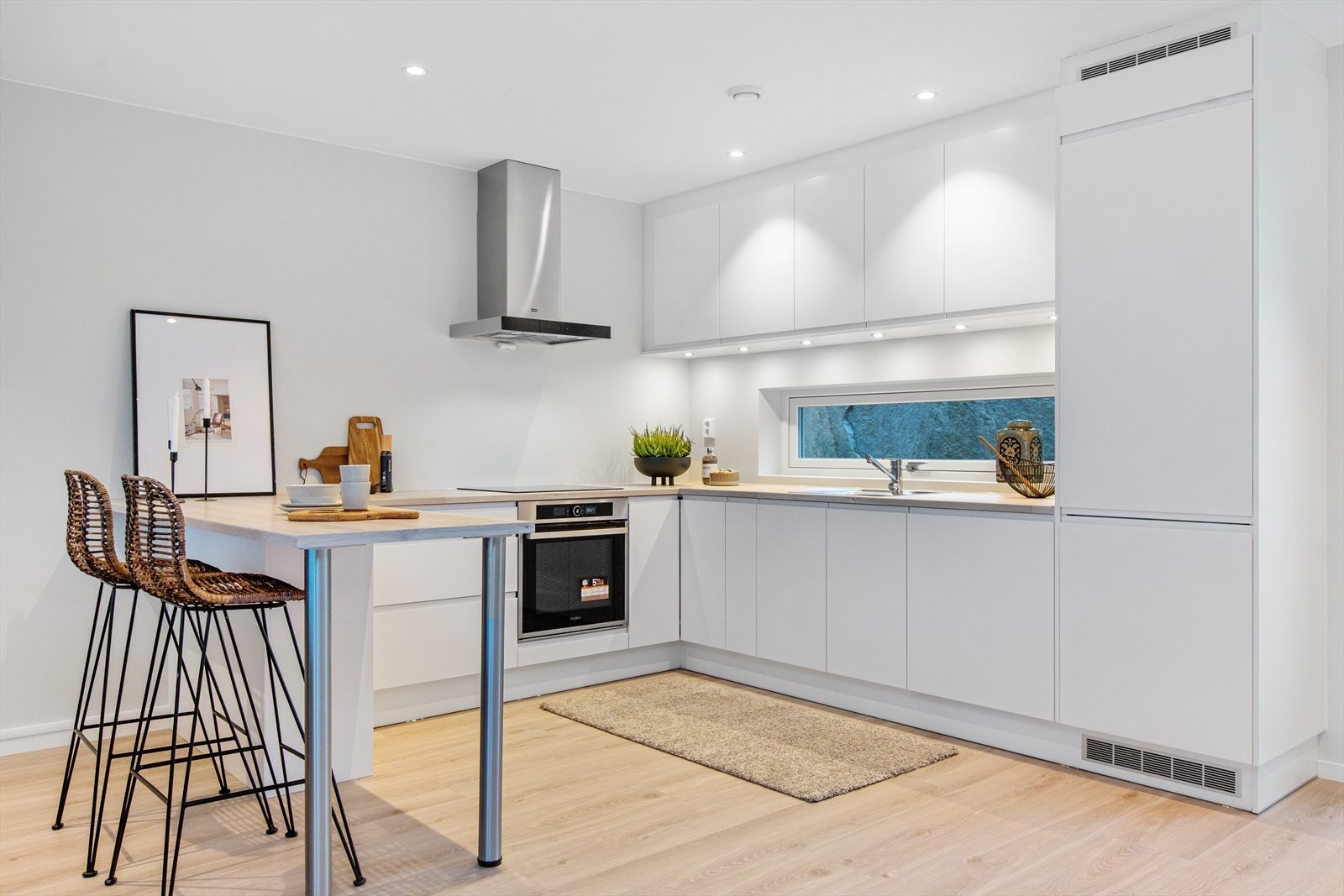 Pen hvit kjøkkeninnredning fra Mesterkjøkken med slette og grepsfrie fronter. Integrerte hvitevarer. Galleribilde