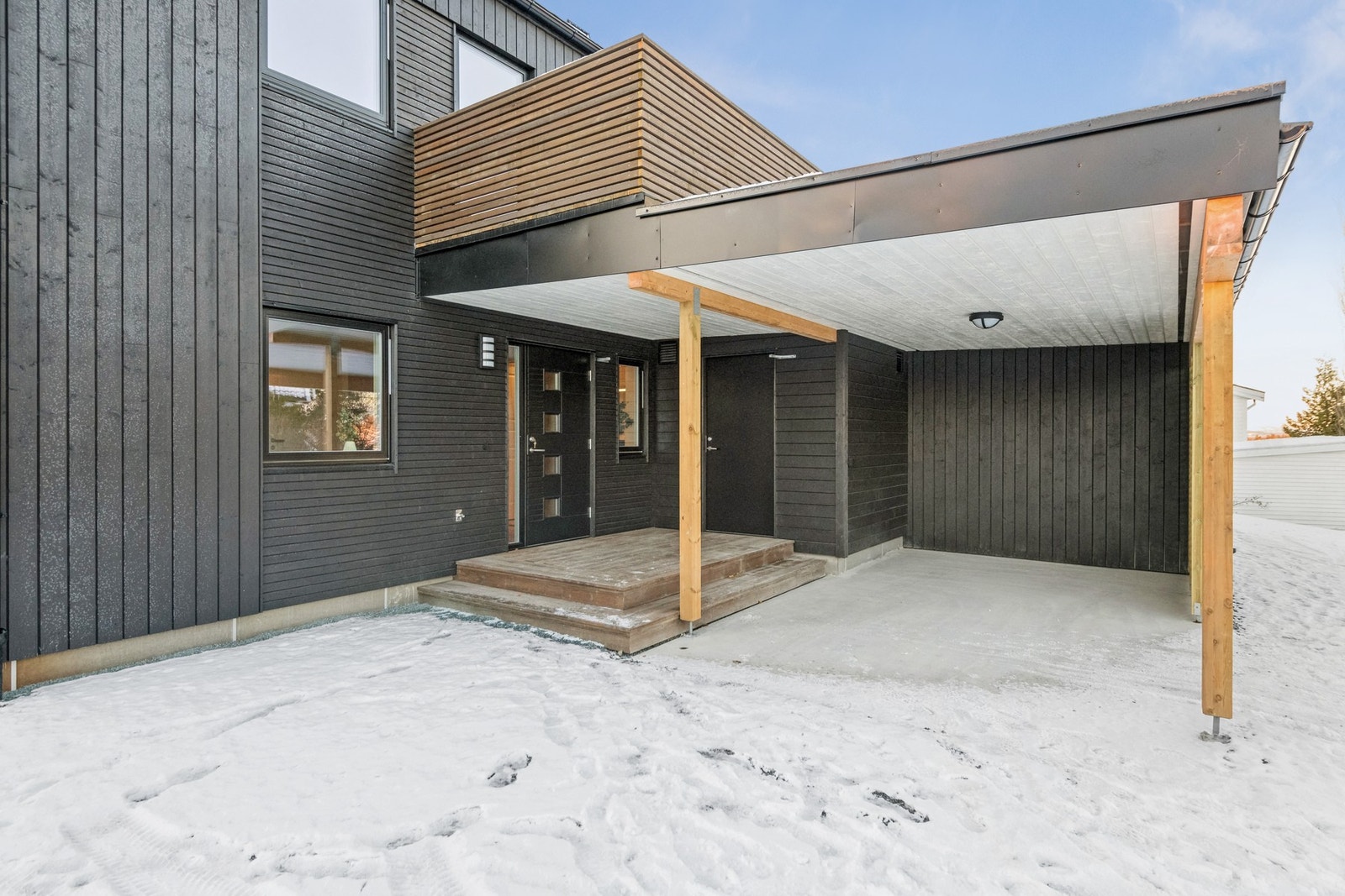 Praktisk inngangsparti med felles tak over carport og inngangsdør. Sportbod rett utenfor inngangsdøra. Galleribilde