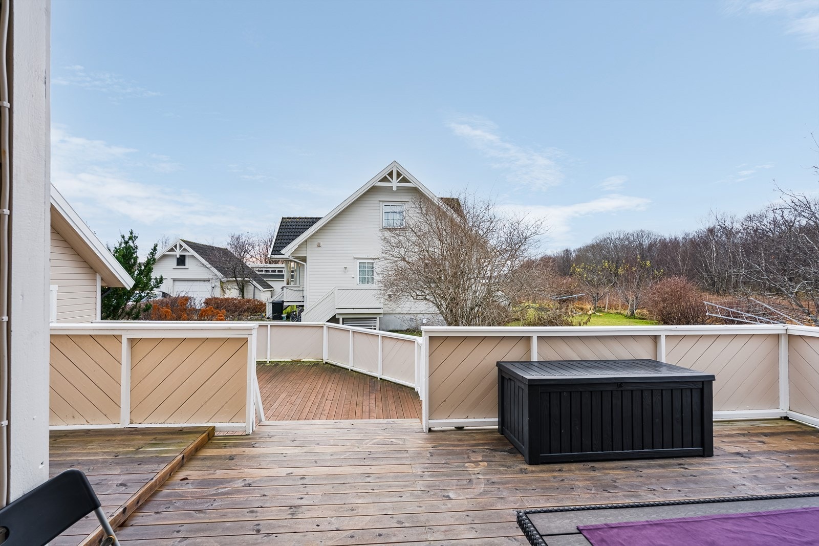 Nedgang til en veranda på ca. 36 m² som streker seg mot uthus, garasje og inngangsparti. Fra veranda er det også nedgang til plen. Galleribilde