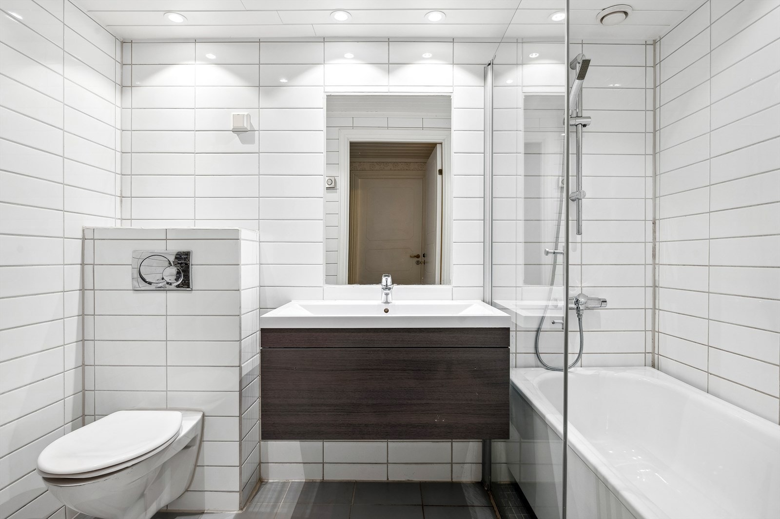 Badet i u. etasje er innredet med en baderomsinnredning med heldekkende servant, speil, veggmontert toalett og badekar. Galleribilde