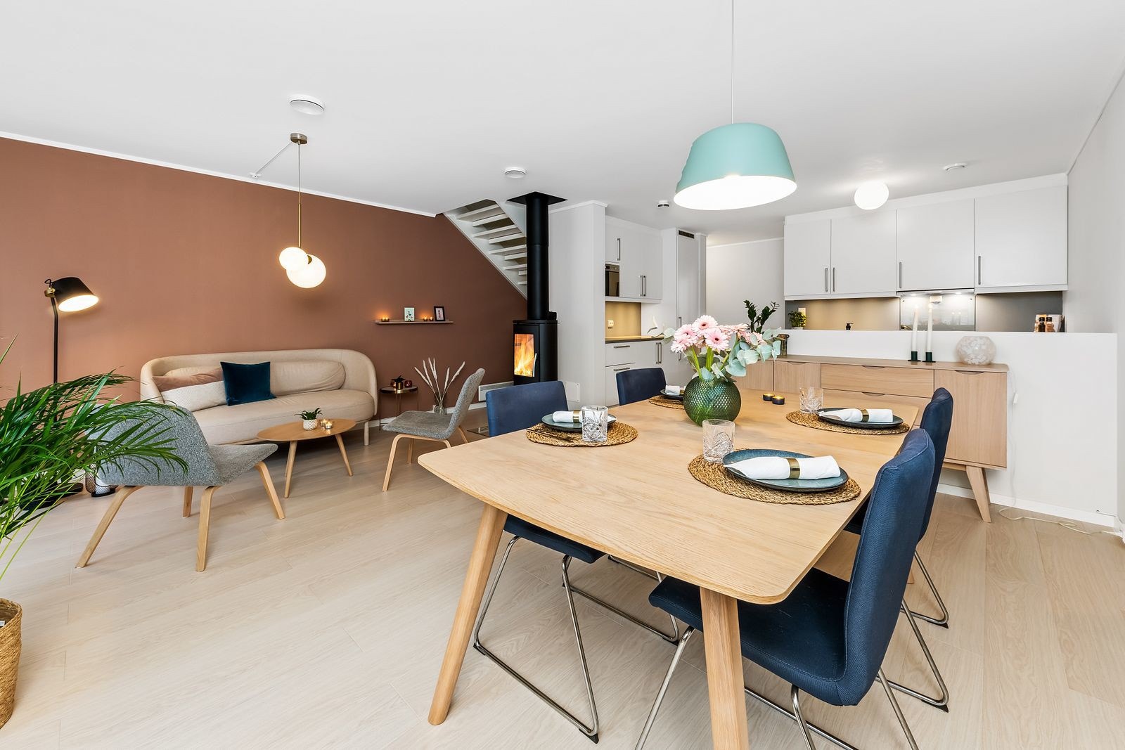 Stuen i første etasje ligger i åpen løsning med kjøkkenet. Det er moderne peisovn og plass til spisebord. Galleribilde