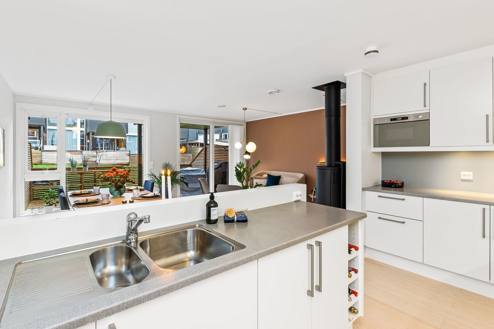 Kjøkkeninnredningen har takoppforede overskap, hvite, slette fronter, vinhyller, belysning og laminerte benkeplater. Galleribilde