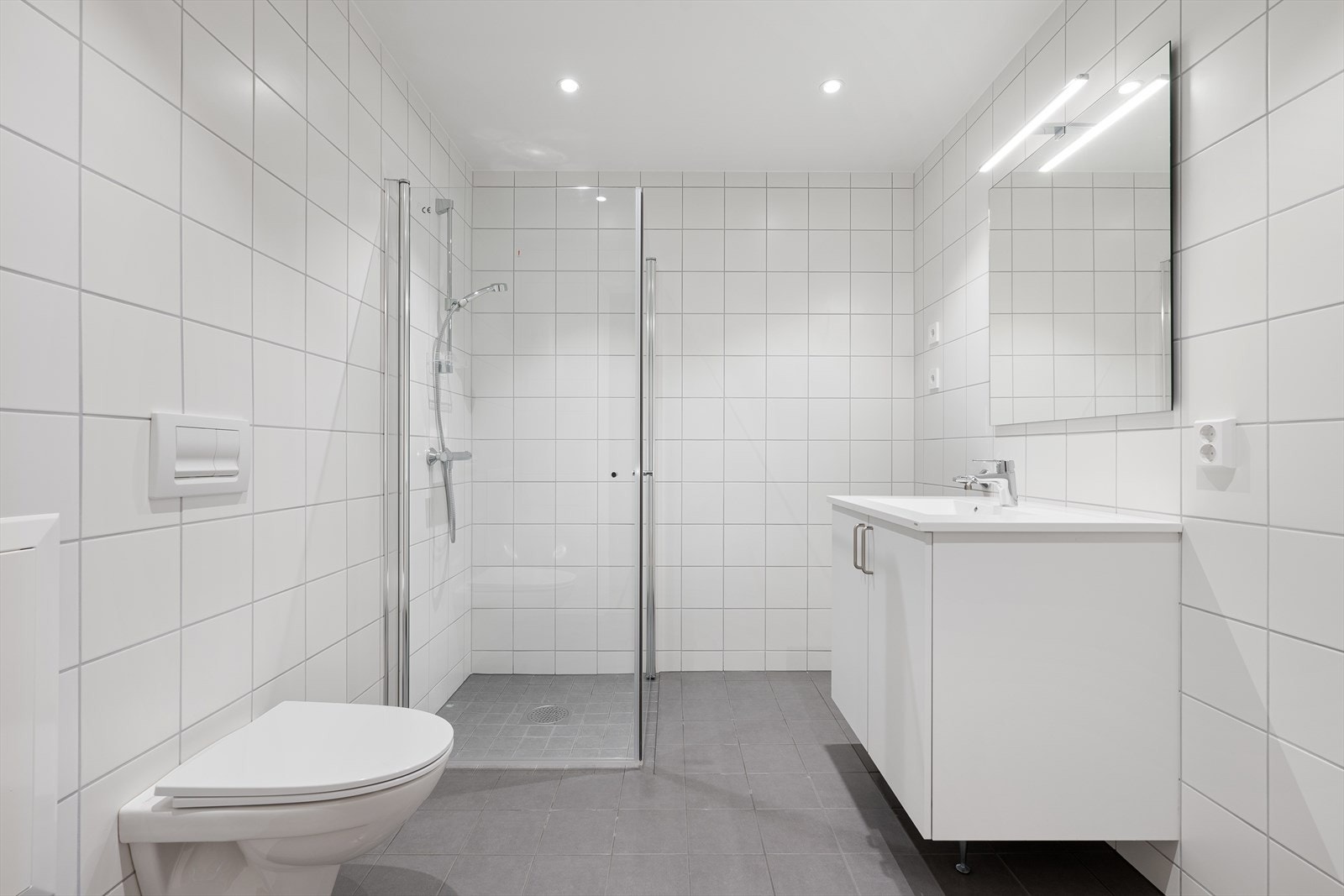 Badet har gulvvarme, dushjørne med glassdører, vegghengt klosett og opplegg for vaskemaskin Galleribilde