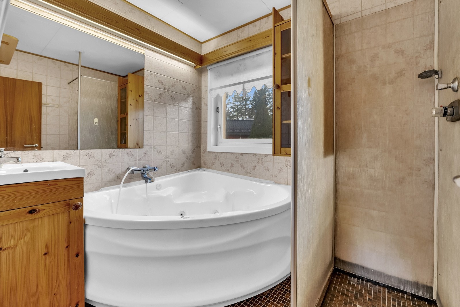 Badet i 1. etasje har både et åpent dusjhjørne og et hjørnebadekar med dusjløsning. Galleribilde