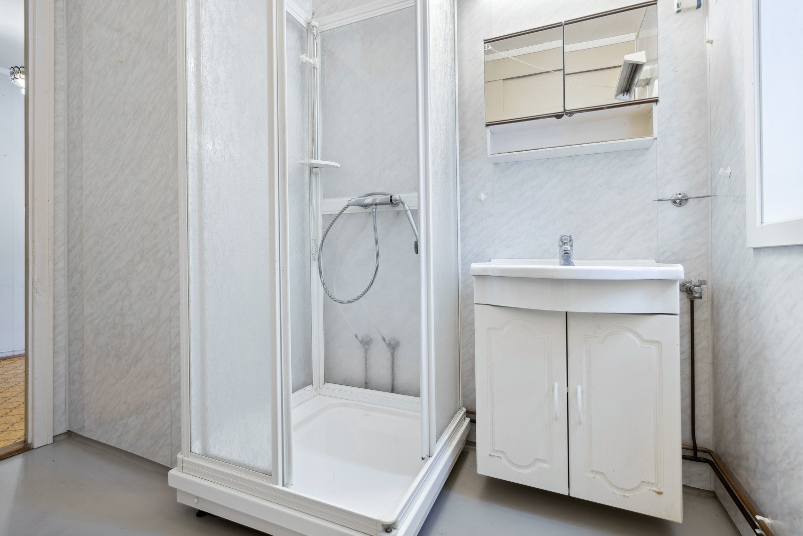 Badet er utstyrt med toalett, servantinnredning og dusjhjørne med glassdører. Galleribilde