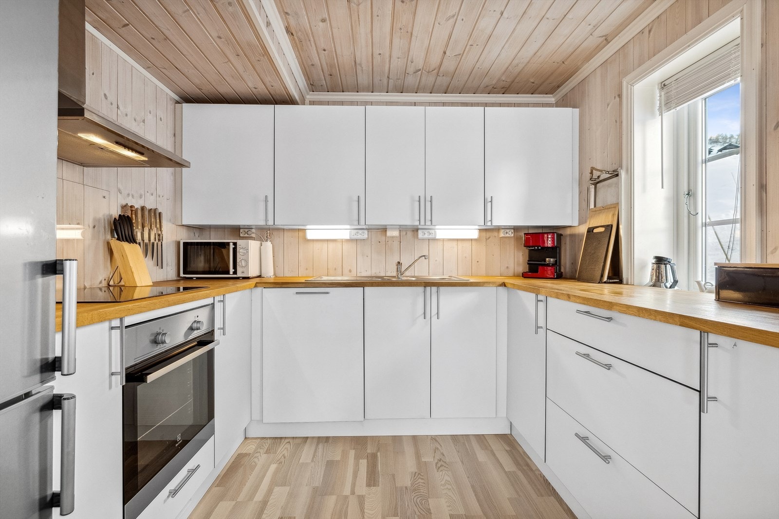 Kjøkkeninnredningen består av glatte fronter, heltre benkeplate med nedfelt dobbel oppvaskkum, glatteplate på vegg bak kokesone og ventilator. Galleribilde