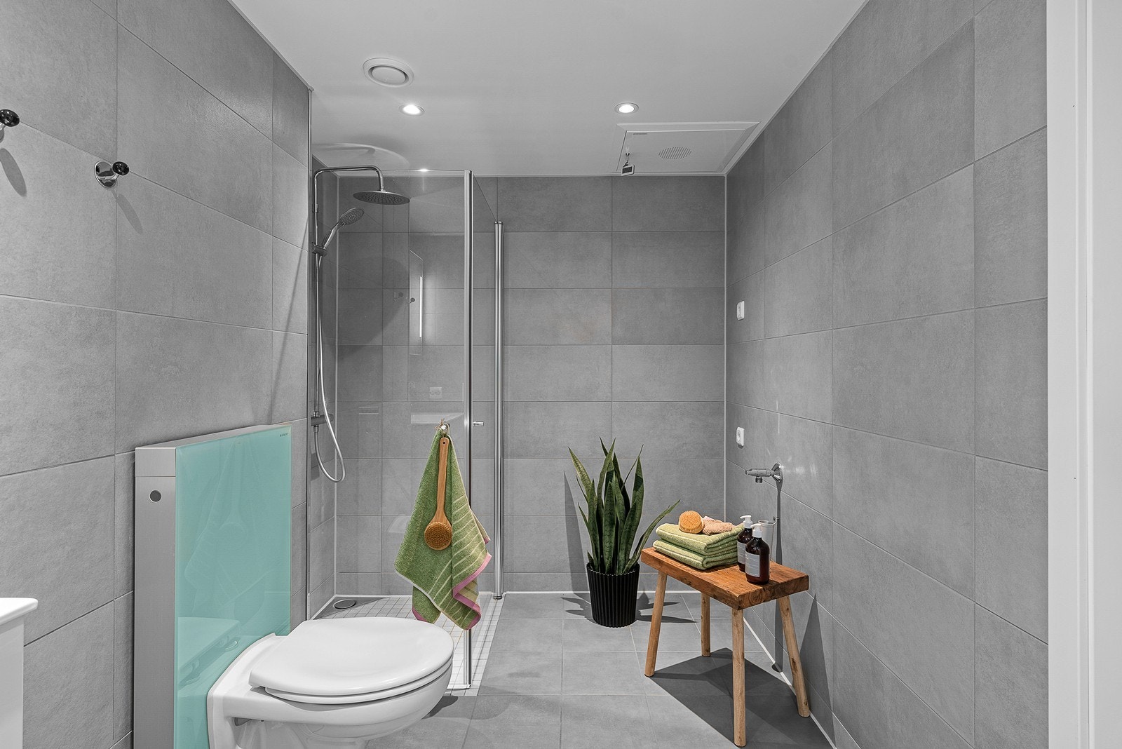 Badet er videre utstyrt med dusjhjørne med innfellbare glassvegger, vegghengt wc, servantinnredning med skuffer og overskap, samt opplegg og plass til både vaskemaskin og tørketrommel. Galleribilde