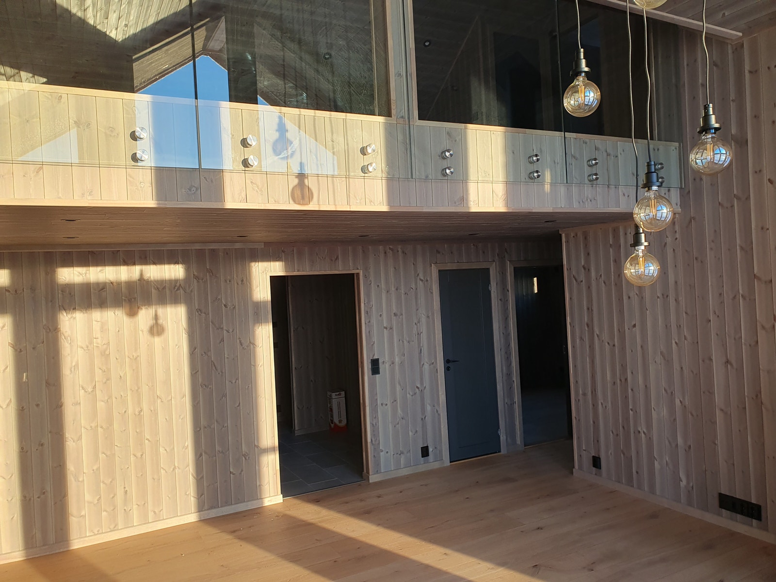 Sola stråler inn på skigardsgrå panel og pendellamper. Galleribilde