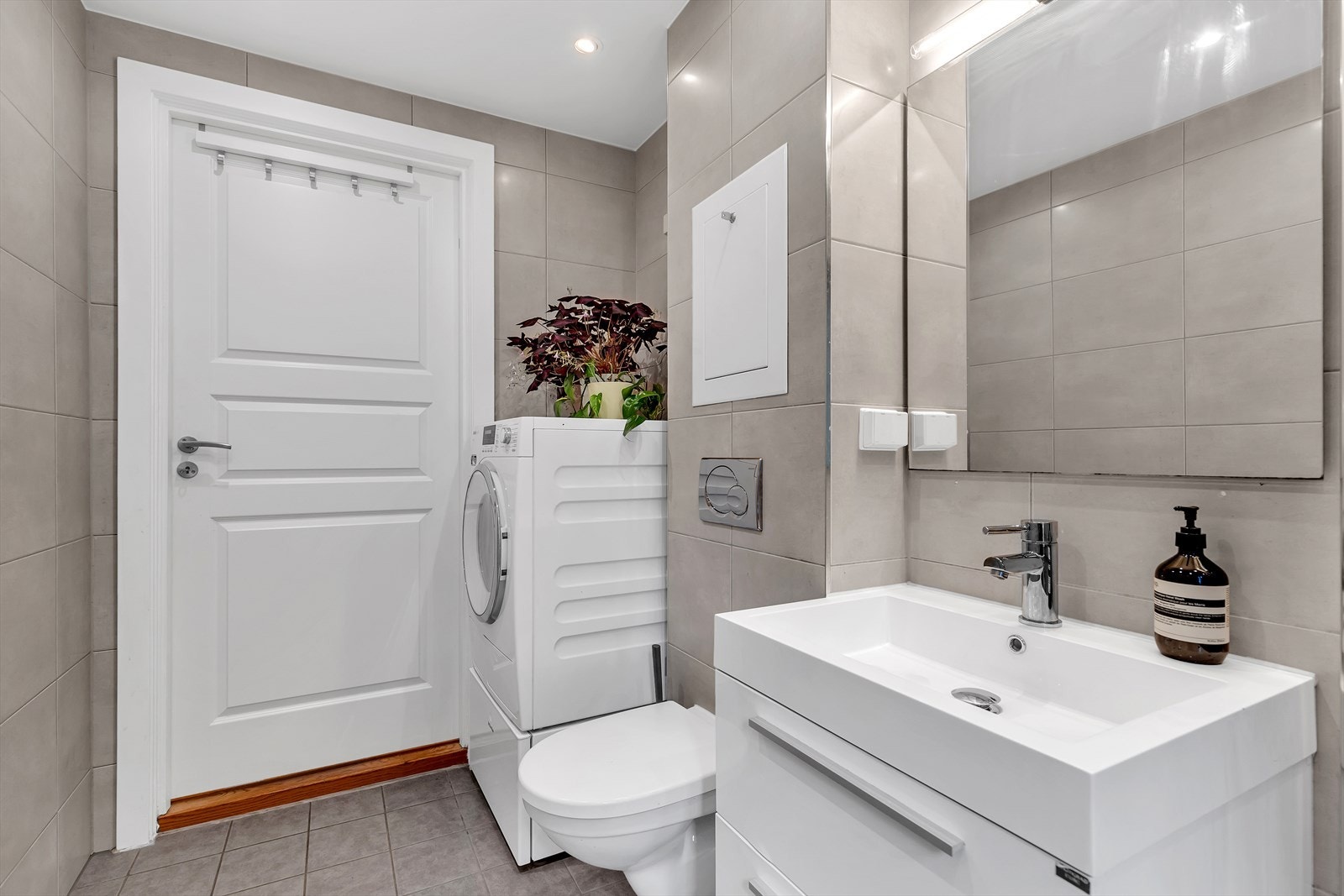 Badet er utstyrt med vegghengt klosett, dusjhjørne med svingbar glassvegg og servant med tilhørende skuffeseksjon. Galleribilde