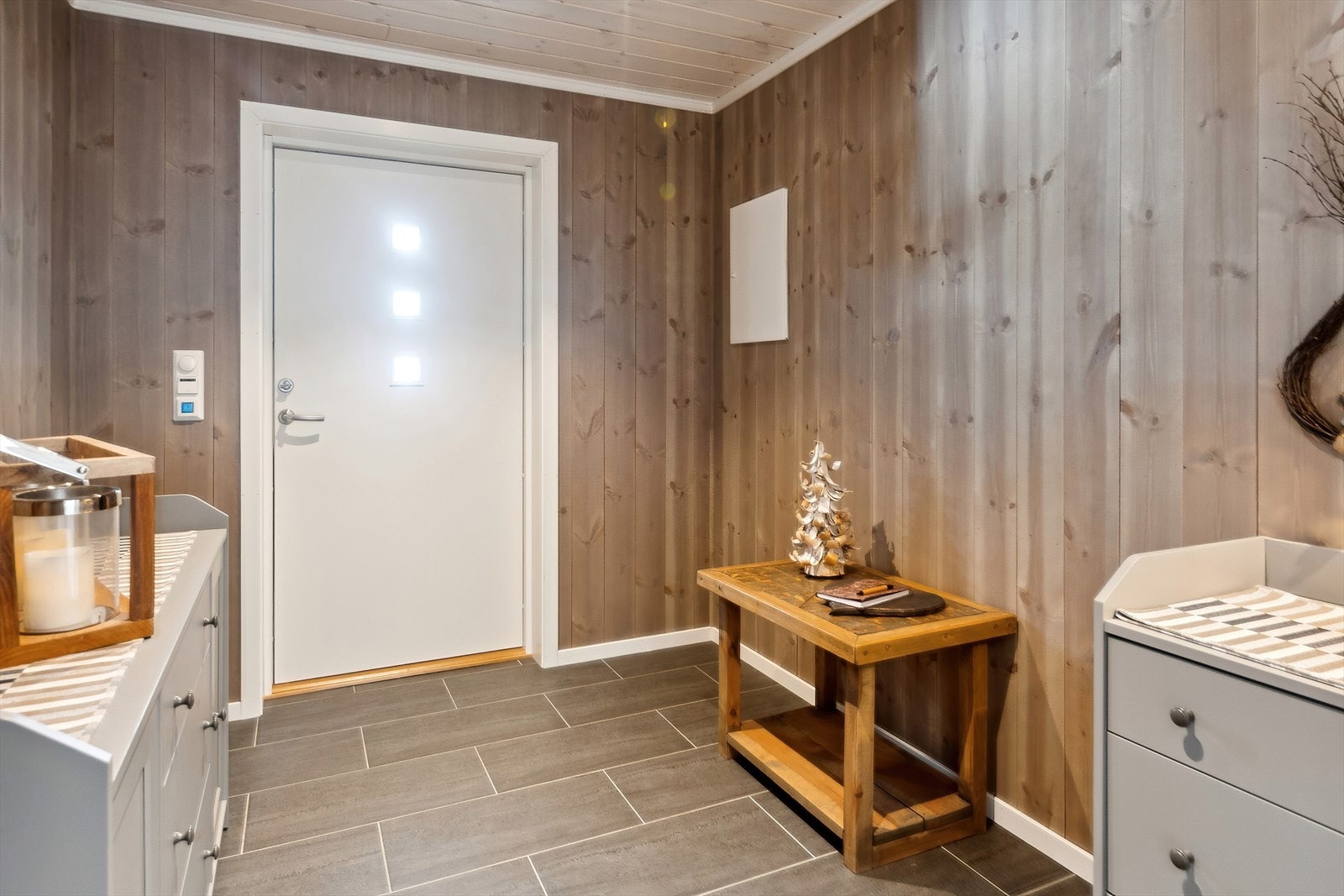 Romslig entré med beiset furupanel på vegger og varme i det flislagte gulvet. Galleribilde