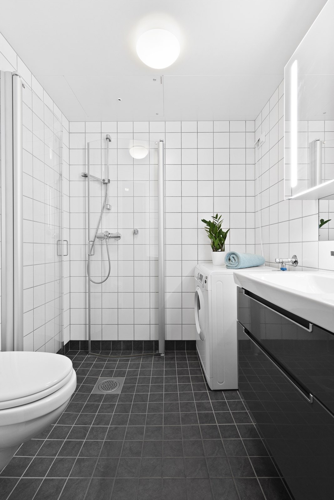 Flislagt bad med varmekabler i gulv, dusj med innfellbare dører og opplegg for vaskemaskin. Galleribilde