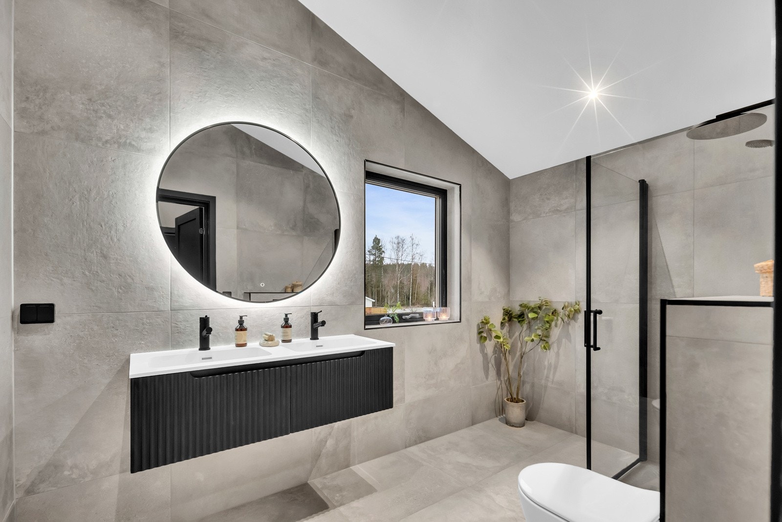 Badet ved hovedsoverom er stilren med store, delikate vegg- og gulvfliser i grått. Galleribilde
