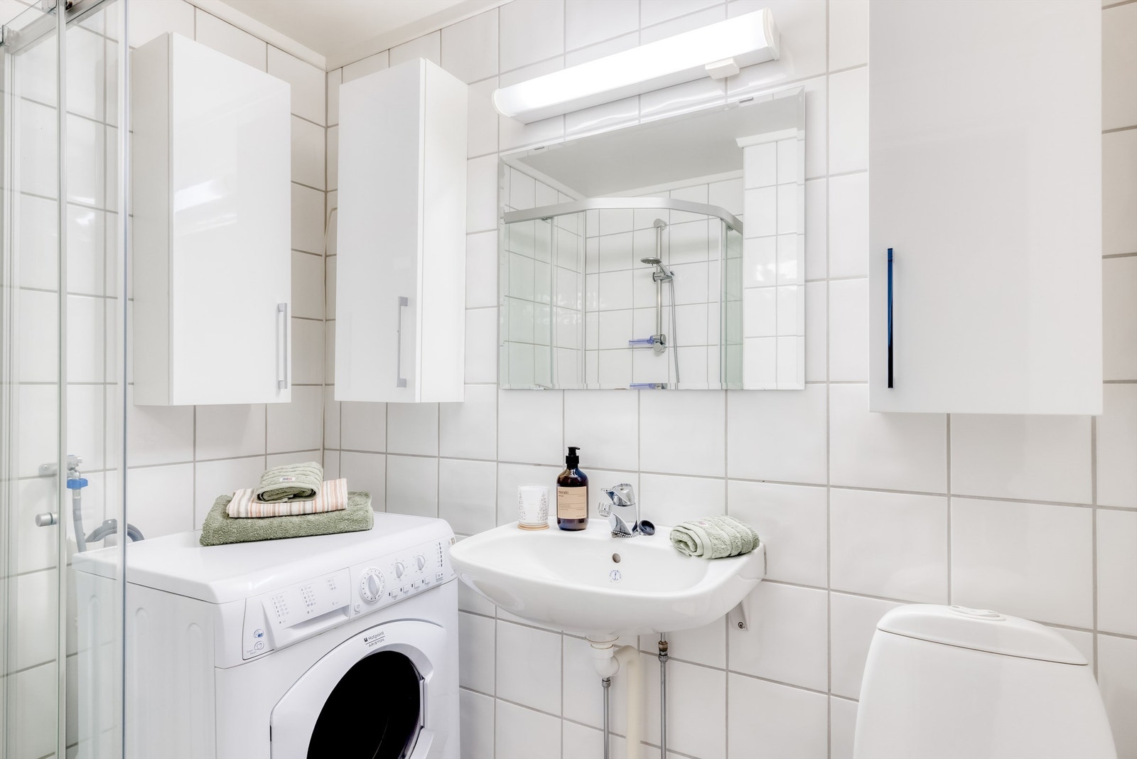 Badet har vegghengt servant med speil og lys over, vegghengte skap, toalett, samt opplegg for vaskemaskin. Vaskemaskinen medfølger salget. Galleribilde