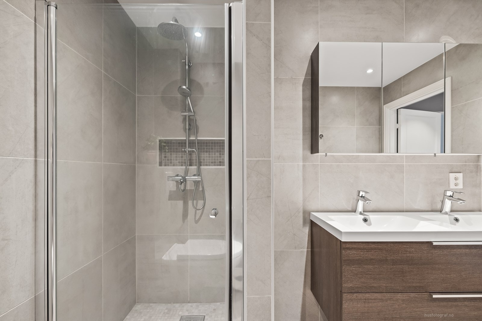 Sanitærutstyr er bestående av baderomsinnredning med 2 nedfelte servanter, veggmontert toalett og dusjvegger/hjørne. Galleribilde