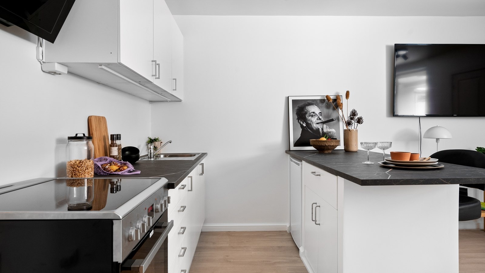 Kjøkkenet er utstyrt med frittstående hvitevarer som kjøleskap og komfyr Galleribilde