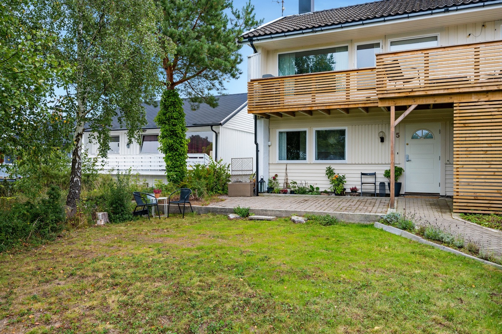 Steinbelagt inngang og platting, og bed med blomster innerst mot husvegg er en fin ramme man kan bygge videre på uteplassen med. Galleribilde