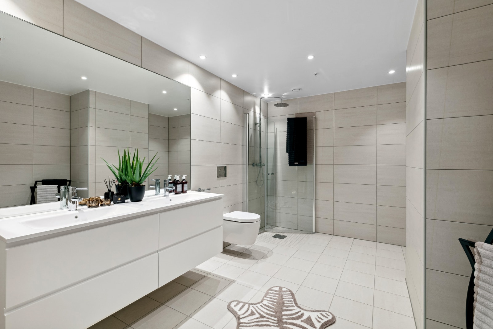 Badet har lyse fliser, opplegg for vaskemaskin og vegghengt wc. Galleribilde