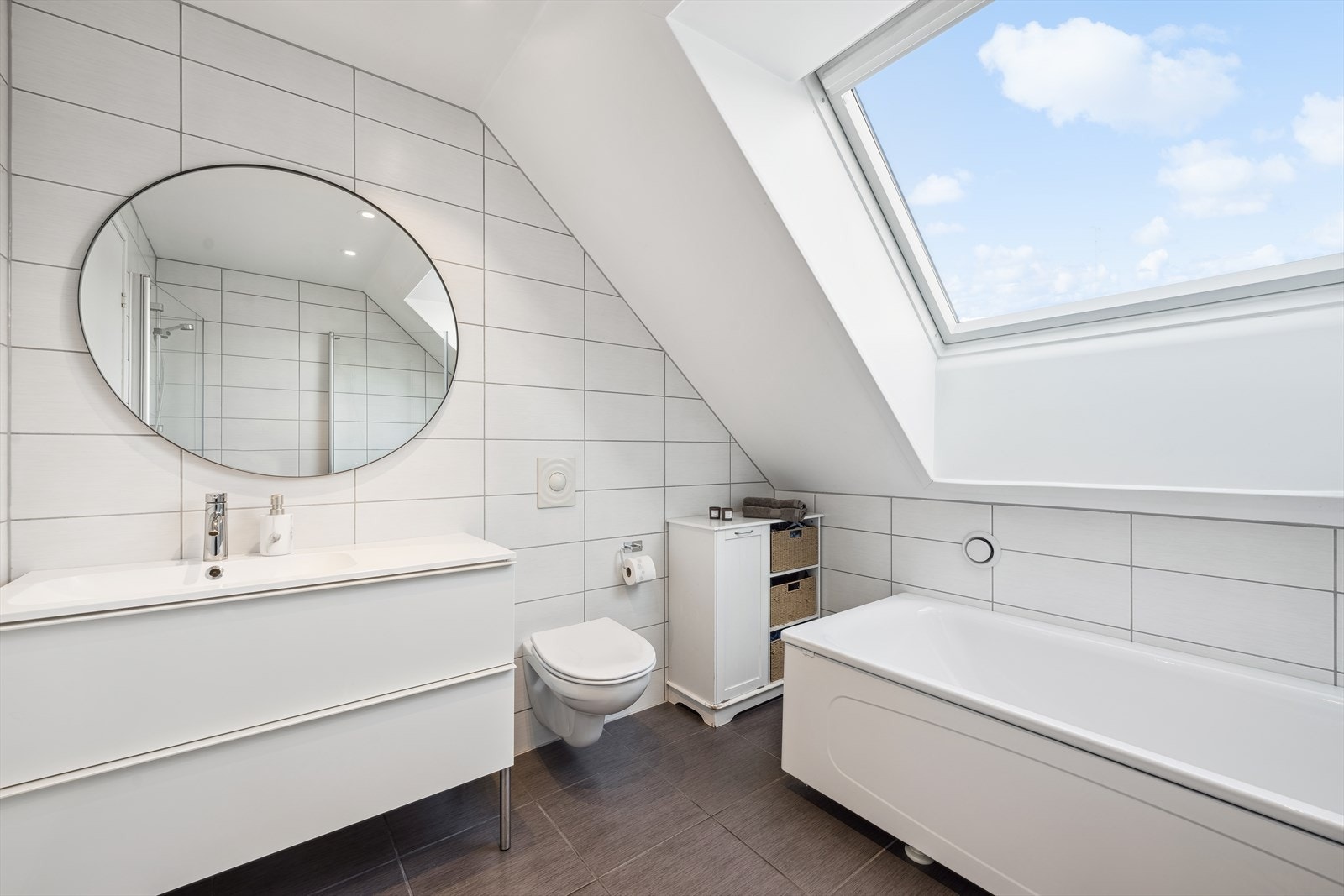 Baderommet er innredet med fin baderomsinnredning, servant, et vegghengt wc, et badekar og dusjhjørne. Galleribilde