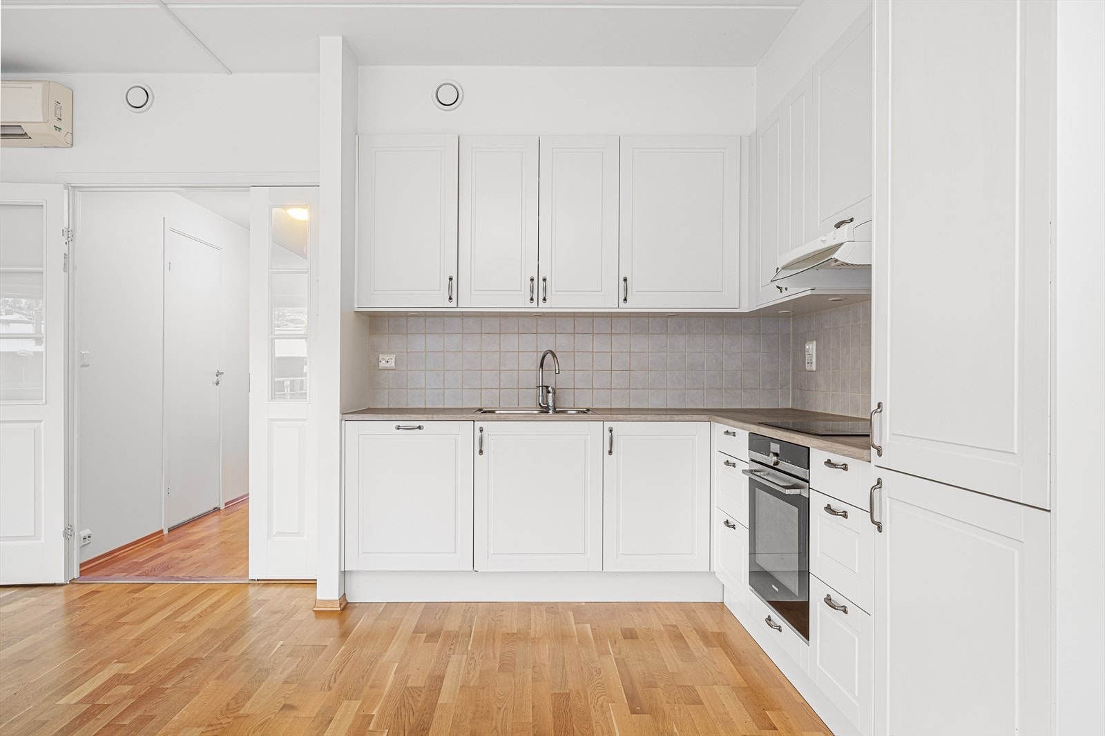 Kjøkkeninnredningen har hvite, profilerte fronter og laminert benkeplate med dobbel oppvaskkum. Galleribilde