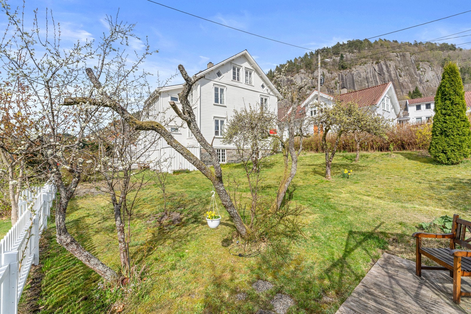 Stor hage med frukttrær som er innegjerdet med stakittgjerde. Galleribilde