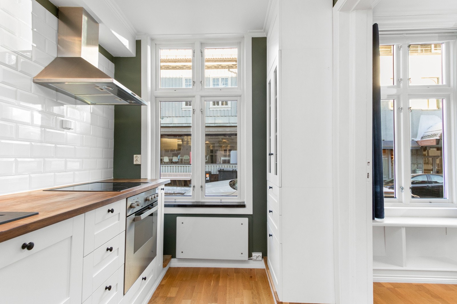 Over benken er den ene veggen kledd med hvite metrofliser, og over kokesonen er det installert både komfyrvakt og ventilator. Galleribilde