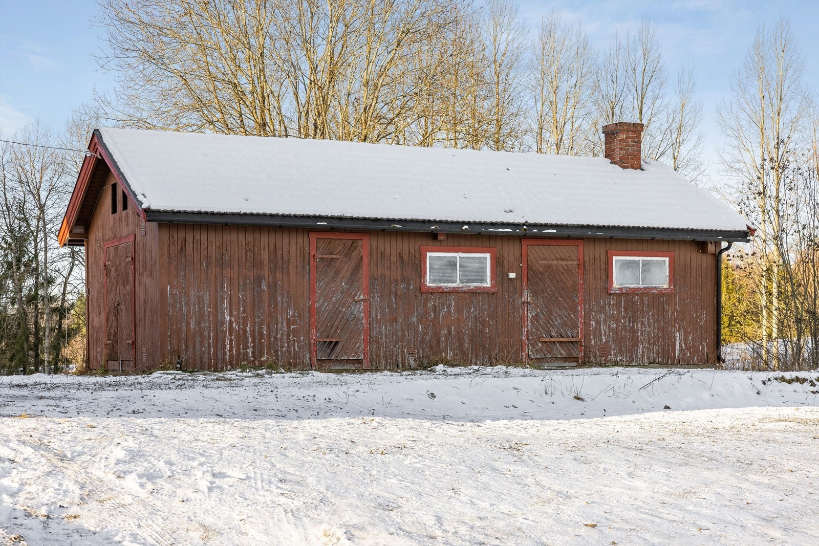 Frittstående uthus med ett innredet rom (gammelt bryggerhus), vedskjul og bod. Galleribilde