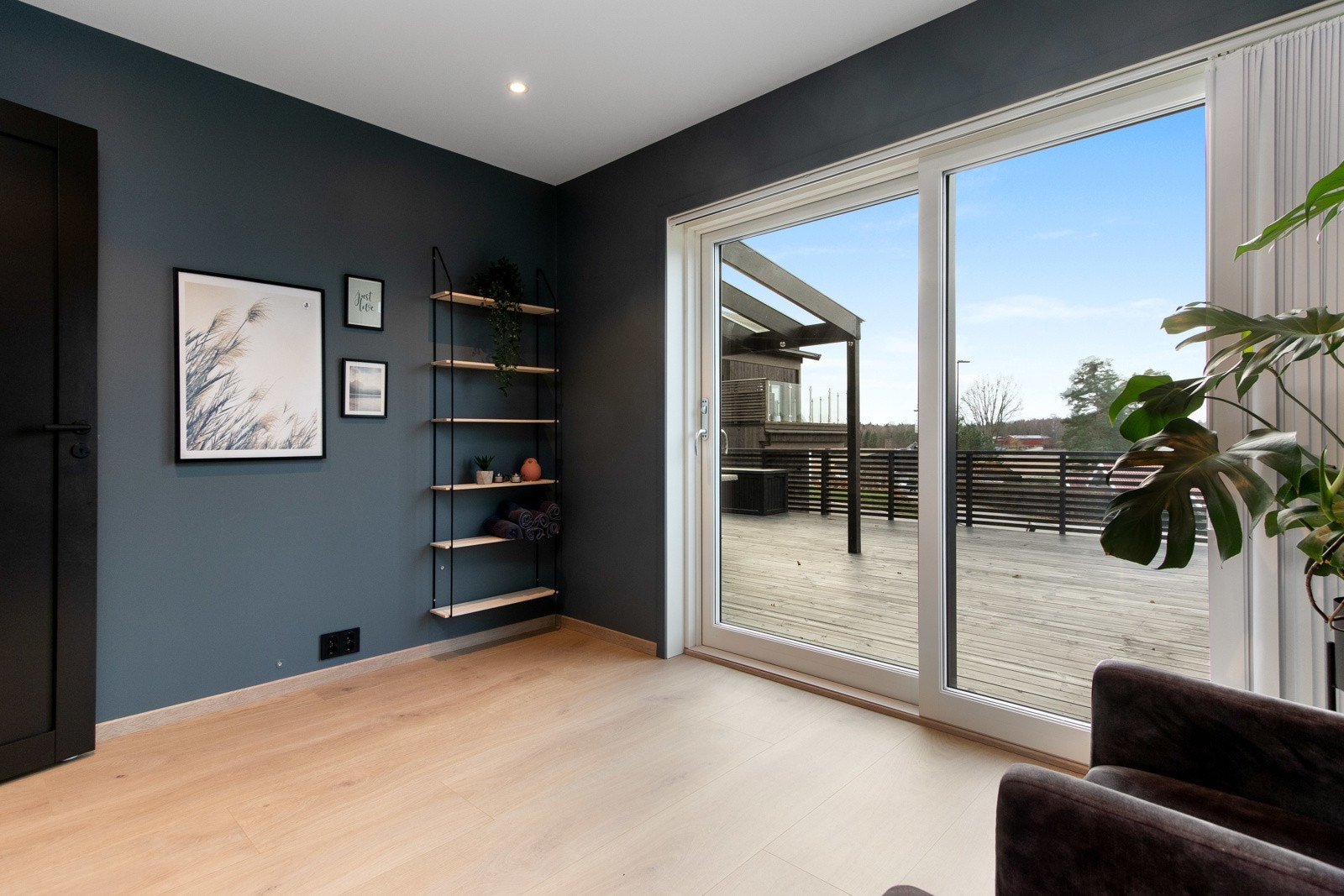 Stuen har enstavs laminatgulv og slette vegger malt i en mørk trendy blåfarge. Galleribilde