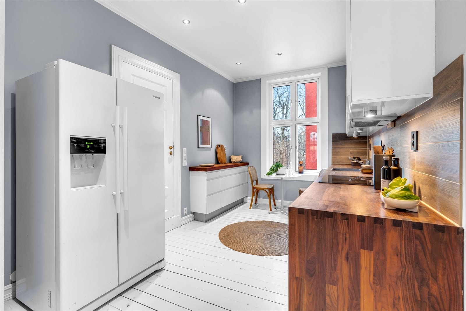 Det er belysning under overskap og fliser på vegg over benkeskap Galleribilde