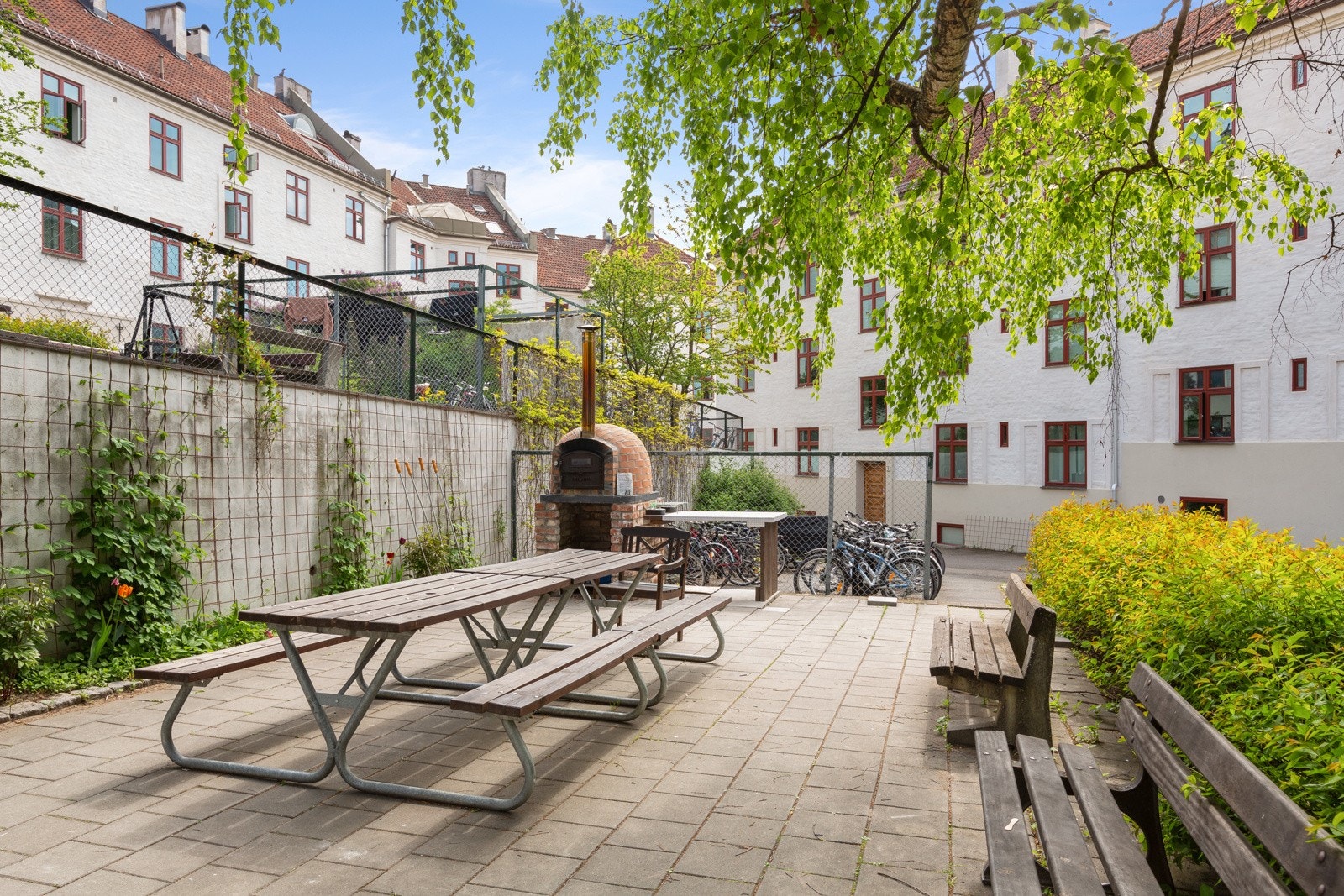 - I bakgården er det lagt til rette for hyggelige sammenkomster. Det er flere sittegrupper og pent opparbeidet med busker, trær og annen beplantning. Steinovnen/Pizzaovnen er flittig brukt blant beboerne - Galleribilde