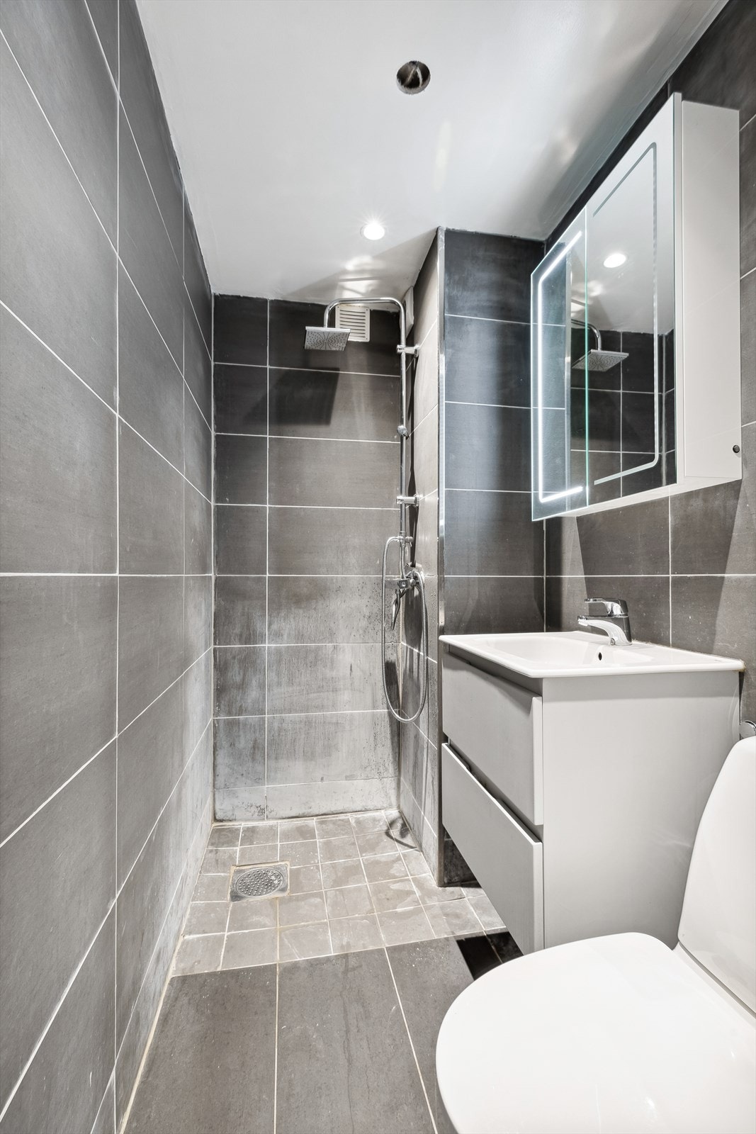 Ett av to flislagte baderom med dusjhjørne og speilskap med integrerte lys. Varmekabler i gulvet. Galleribilde