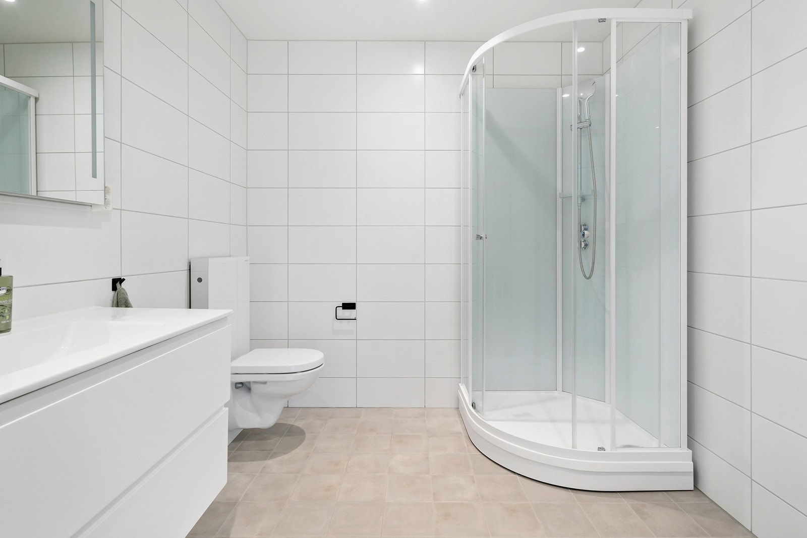 Badet i første etasje har fliser på gulv og vegg. Praktisk med dusjkabinett. Galleribilde