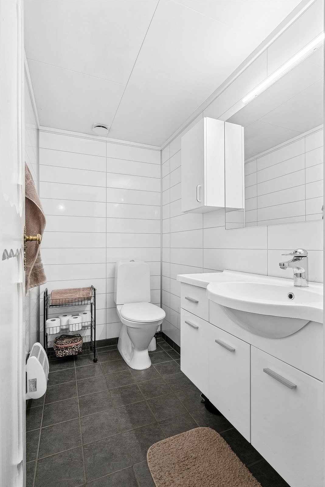 Bad i kjeller. Badet er innredet med servant, gulvmontert toalett og panelovn. Galleribilde