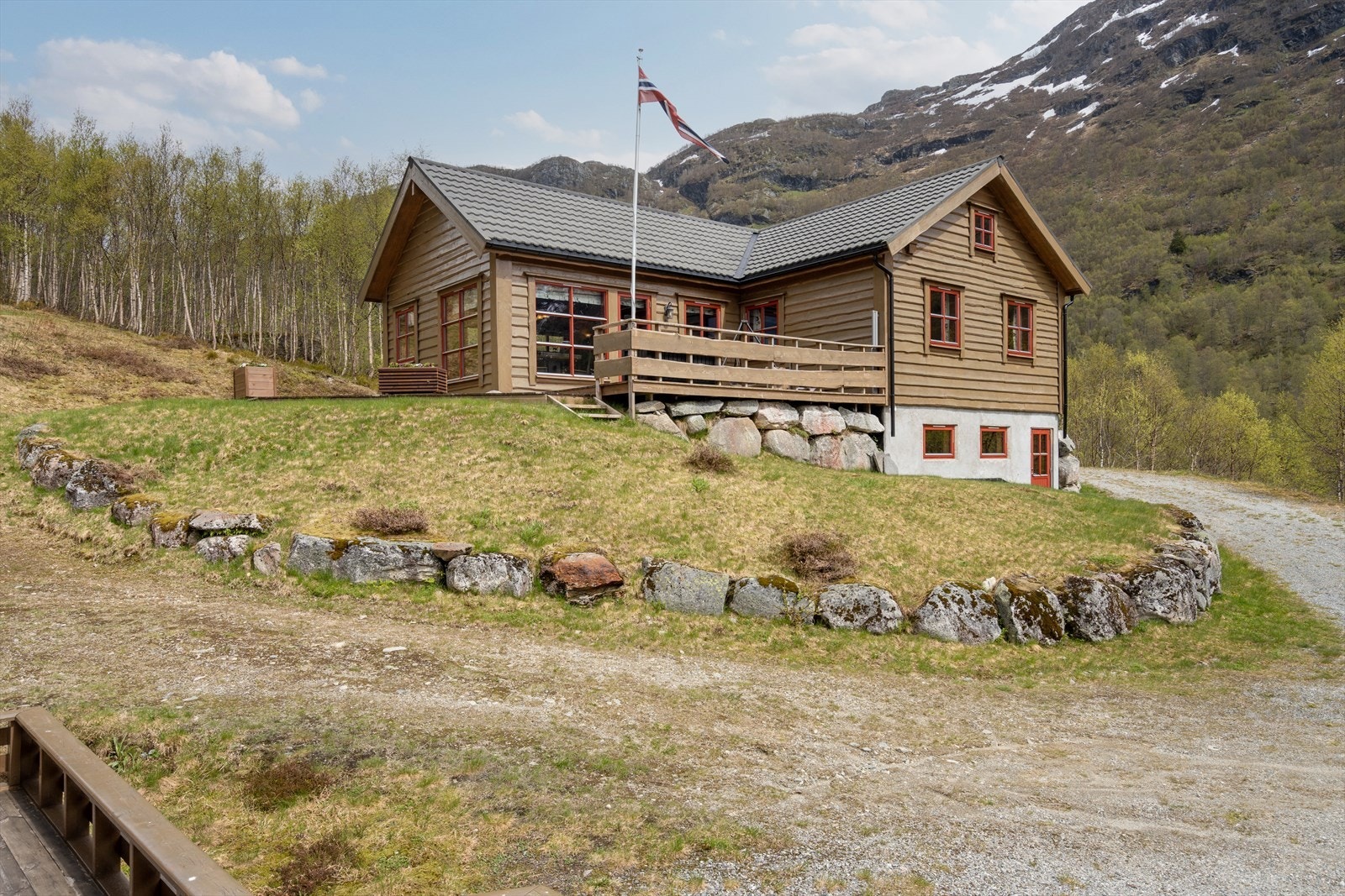 Tomten er opparbeidet med plen, natursteinsmurer og gruset gårdsrom Galleribilde