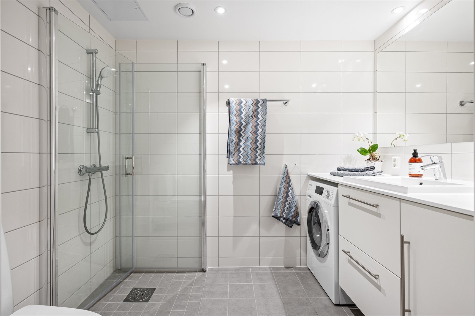 Badet har flislagte overflater, stort speil og opplegg til vaskemaskin. Vannbåren gulvvarme, noe som gir en behagelig opplevelse Galleribilde