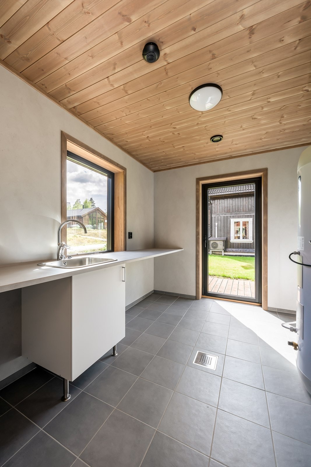 Boligen har et praktisk vaskerom/bod med adkomst fra entré, samtidig som det er direkte adkomst ut til sørvestvendt terrasse. Her er det flis på gulv, baderomsplater Fibo Soft Cement på vegger og beiset trepanel i himling. Galleribilde