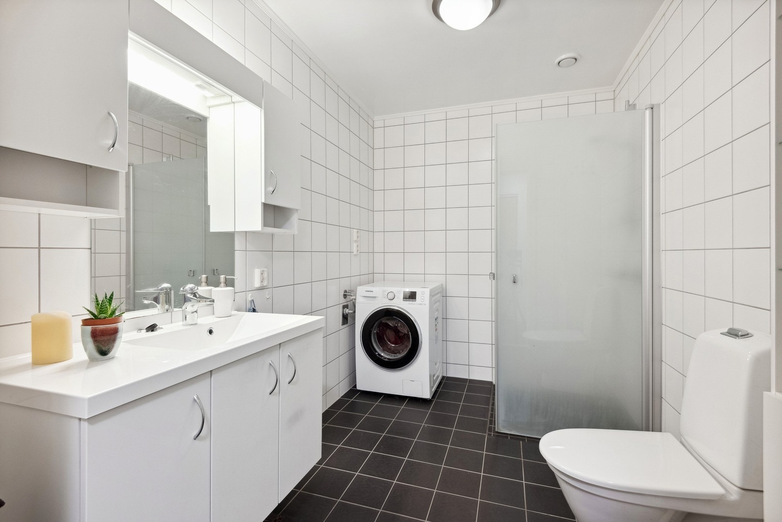 Flislagt bad med opplegg for vaskemaskin. Det er vannbåren varme i gulvet. Galleribilde