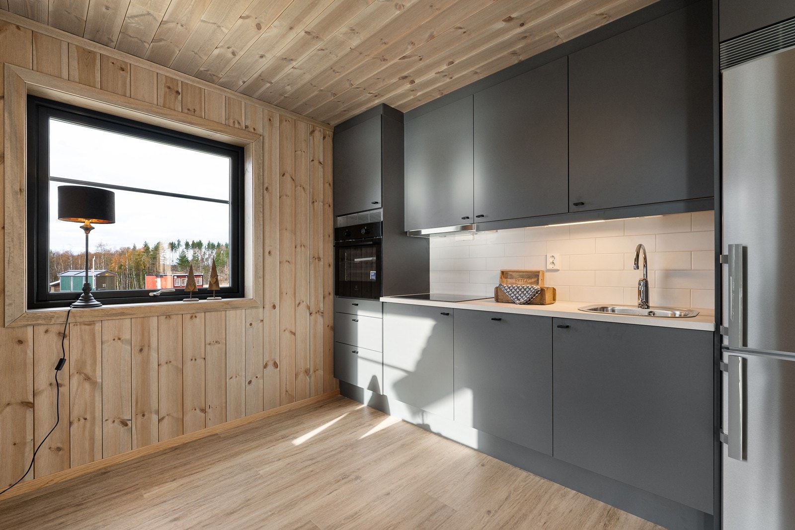 Innredningen har slette, grå fronter med sorte grep og hvit laminatbenkeplate med nedfelt oppvaskkum. Galleribilde