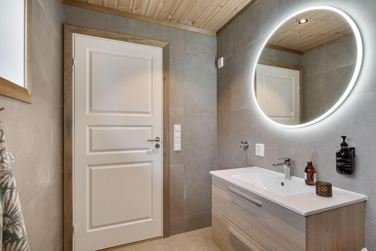 Innredningen har heldekkende servant over skuffeseksjon og rundt speil med belysning.
Det er opplegg for vaskemaskin på badet. Galleribilde