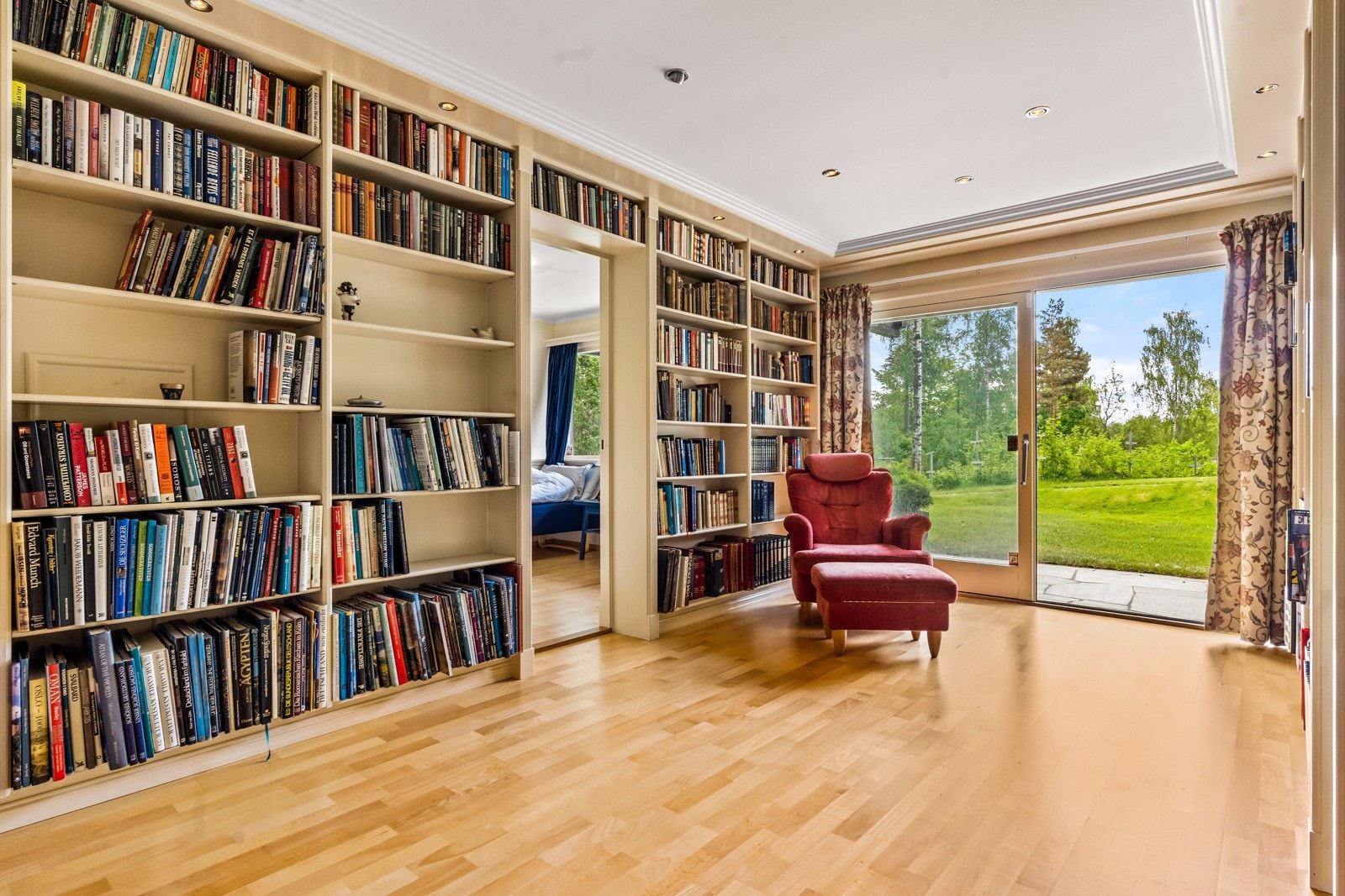 Underetasjen har et stort bibliotek med skyvedører til markterrasse og hage. Plassbygde bokhyller fra gulv til tak på tre av fire vegger. Inngang herfra til 2 soverom. Galleribilde