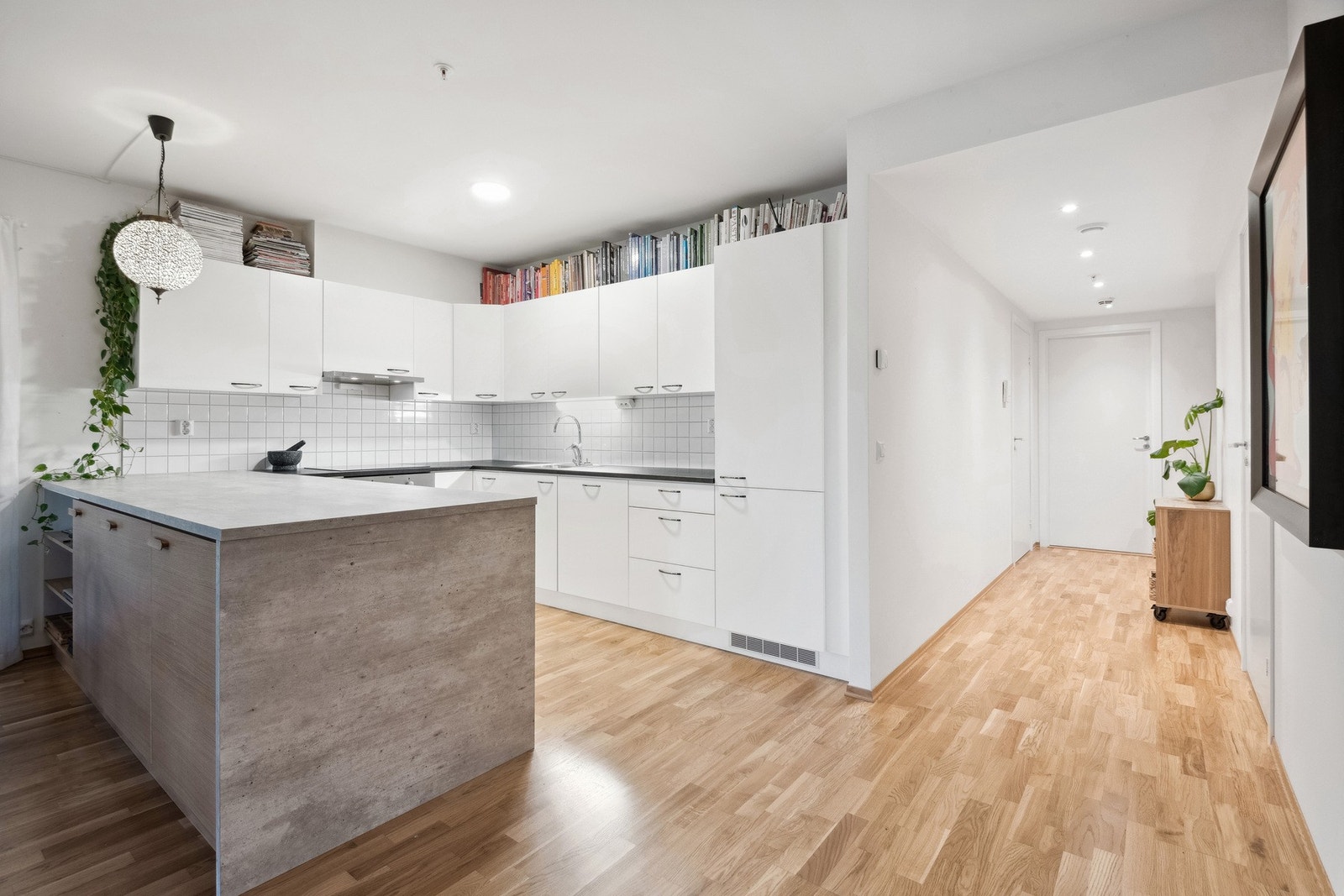 Lyst og innbydende kjøkken med internerte hvitevarer og en romslig kjøkkenøy. Galleribilde