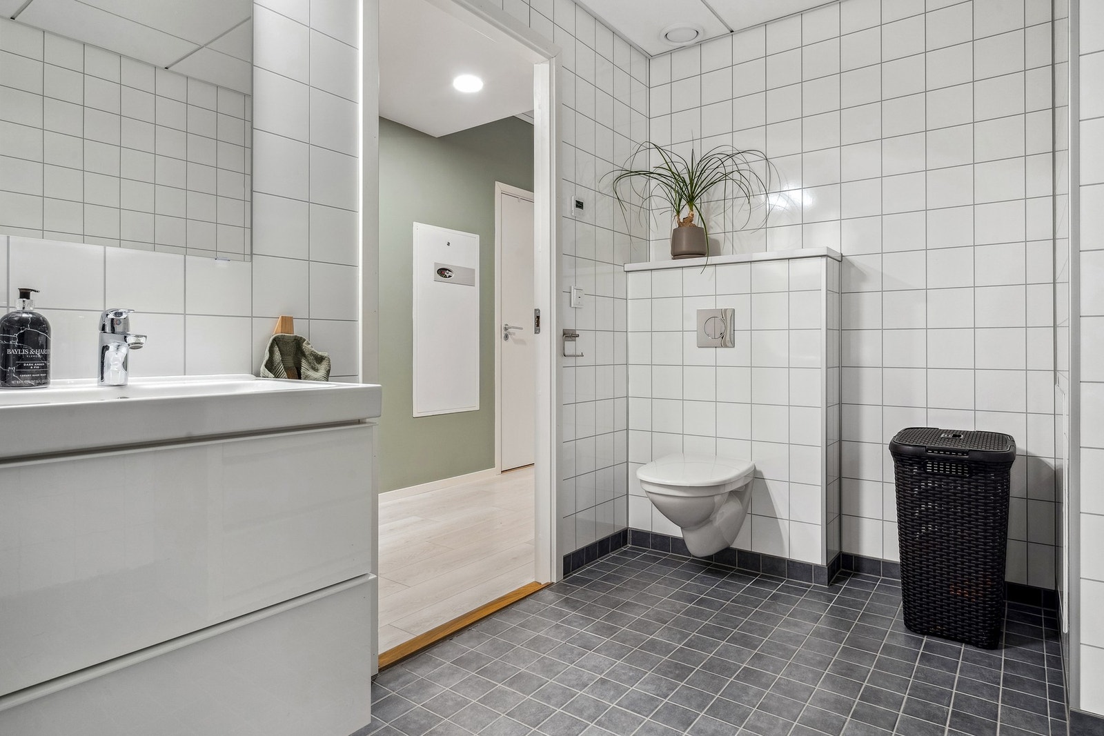 Bad med flislagt gulv og vegghengt klosett. Galleribilde