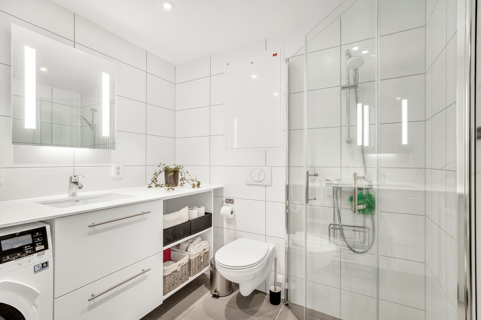 Pent og lyst baderom med opplegg for vaskemaskin. Galleribilde