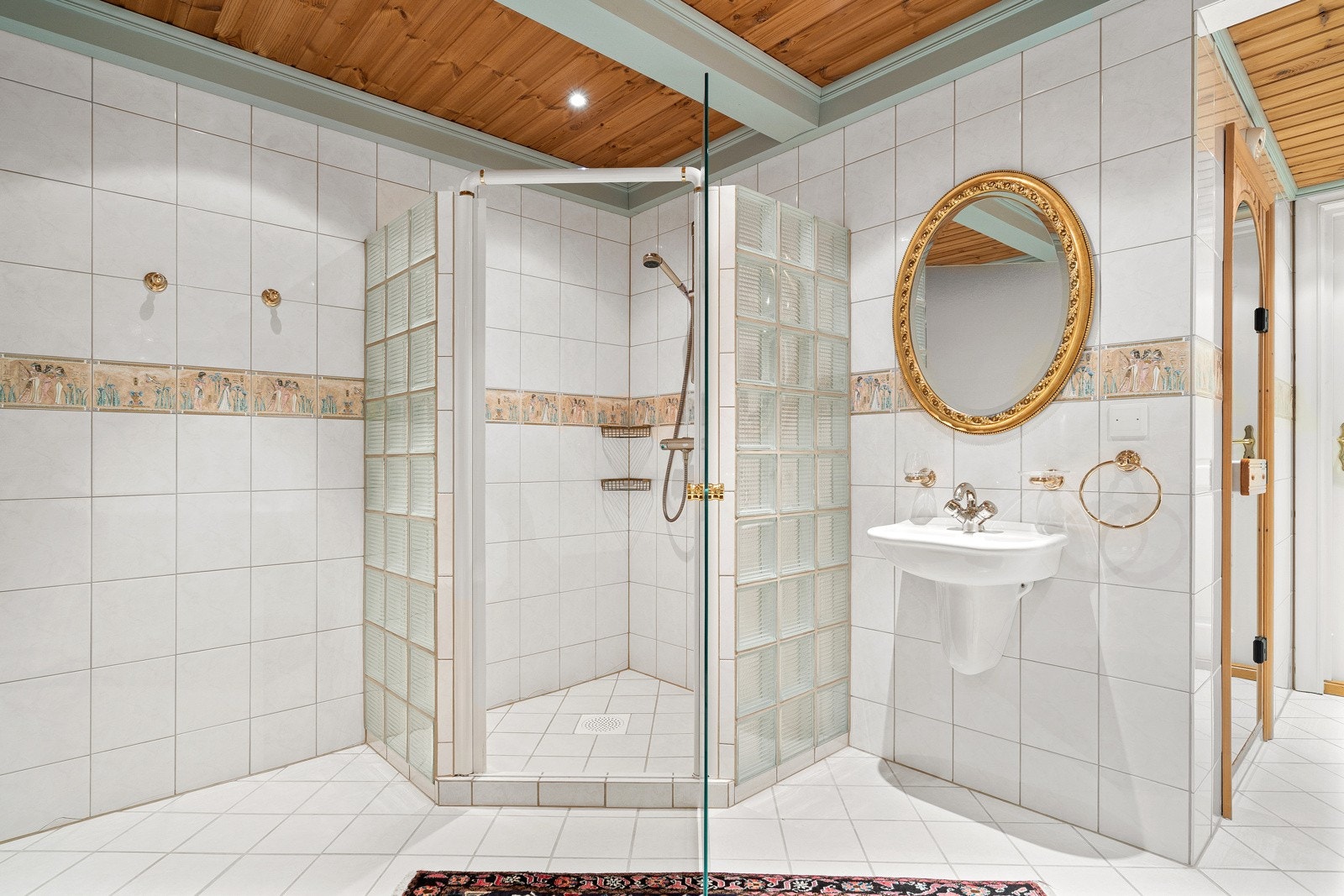 Stort dusjhjørne med lekre glassfliser og videre inngang til badstue. Galleribilde