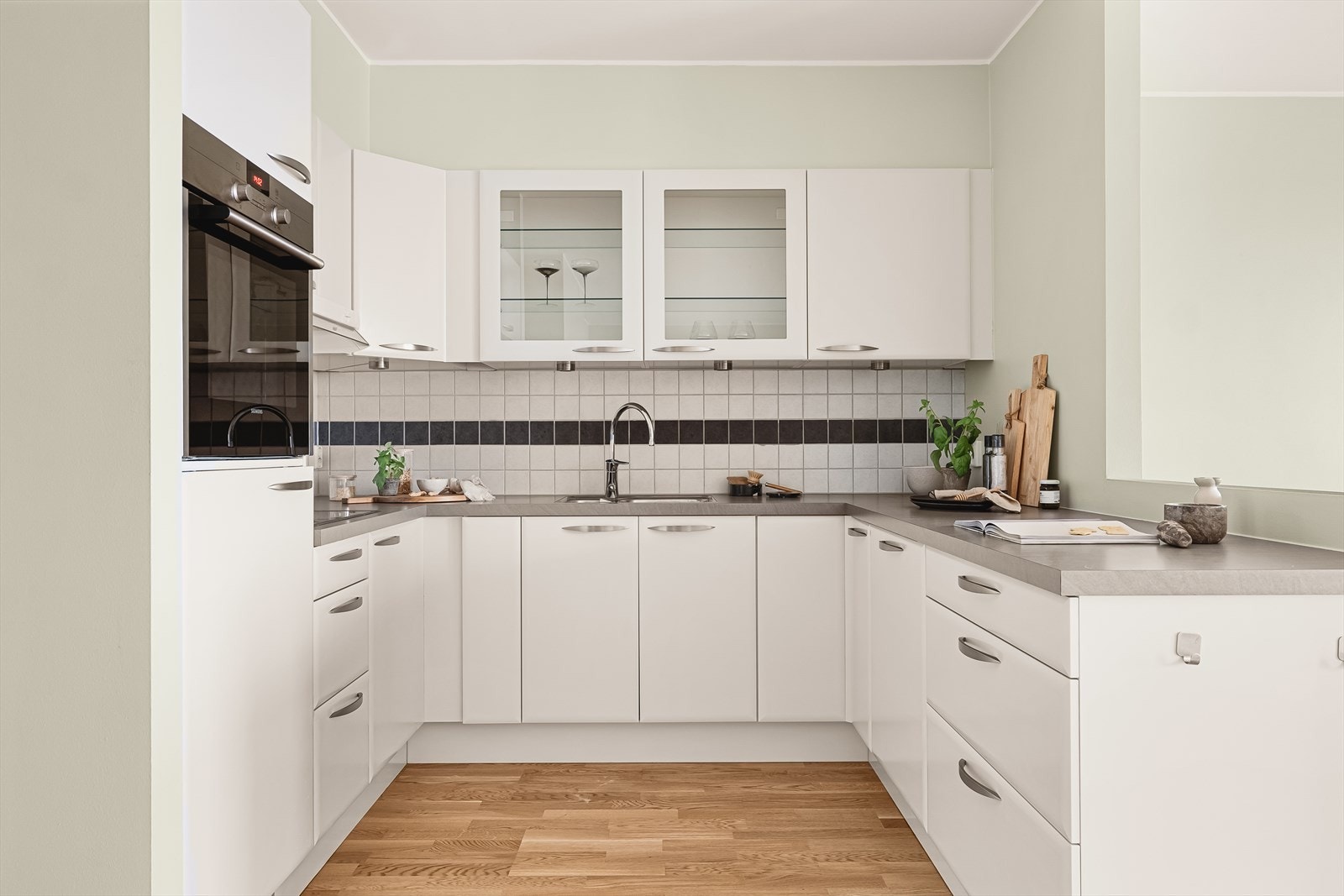 Moderne og tidløst kjøkken med hvite slette fronter og laminat benkeplate med nedfelt stål vaskebeslag. Galleribilde