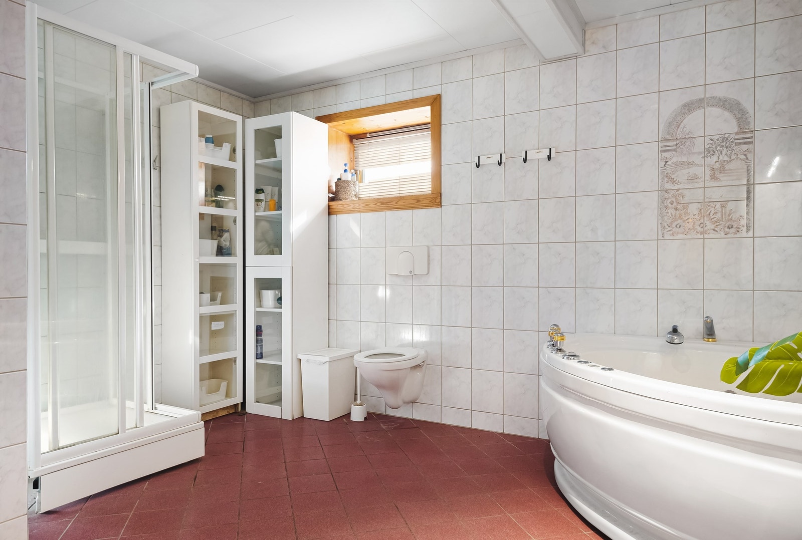 Badet er innredet med servantskap med overskap og speil, side-skap, badekar, toalett og dusjhjørne Galleribilde