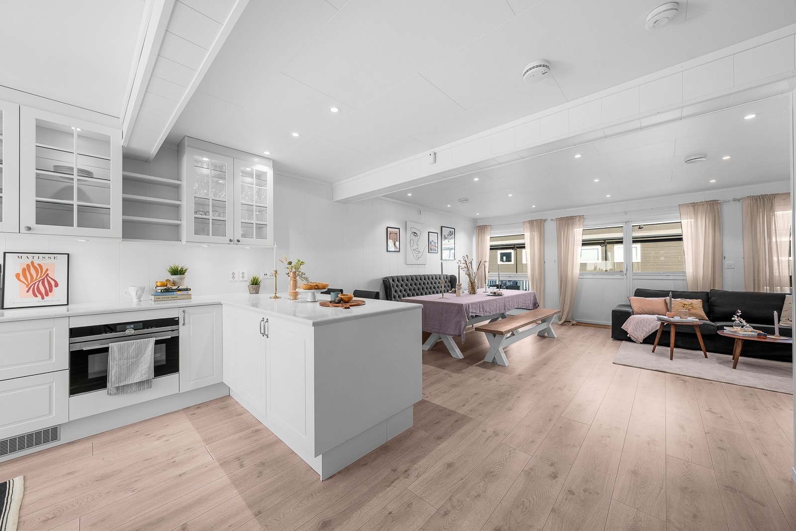 I hver ende av den åpne stue-/kjøkkenet er det store vinduer som bidrar til gjennomgående dagslys. Galleribilde