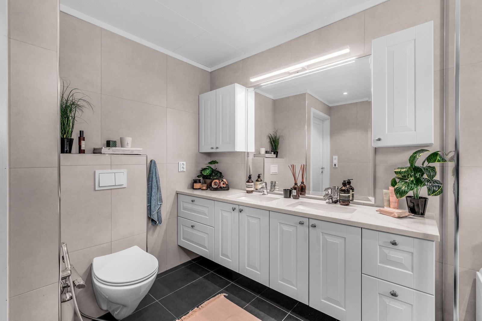 Overlimt dobbelservant i benkeplate av polert kvartskompositt og et stort speil med belysning. Galleribilde