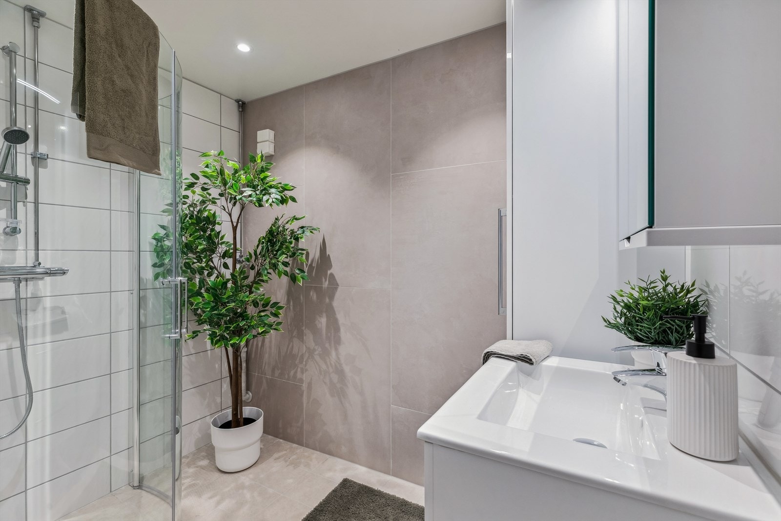 Lekkert bad med varmkabler, servant med servantskap, overskap med speildører, høyskap, hjørnedusj med innfellbare glassdører Galleribilde