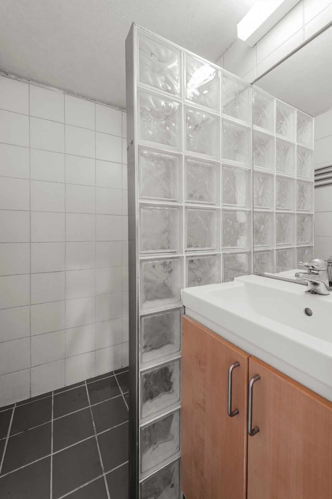 Fliser på gulv og vegger. Dusj med dusjvegg i glassbygger stein. Baderomsinnredning med skap under servant. Varmekabler i gulv. Galleribilde