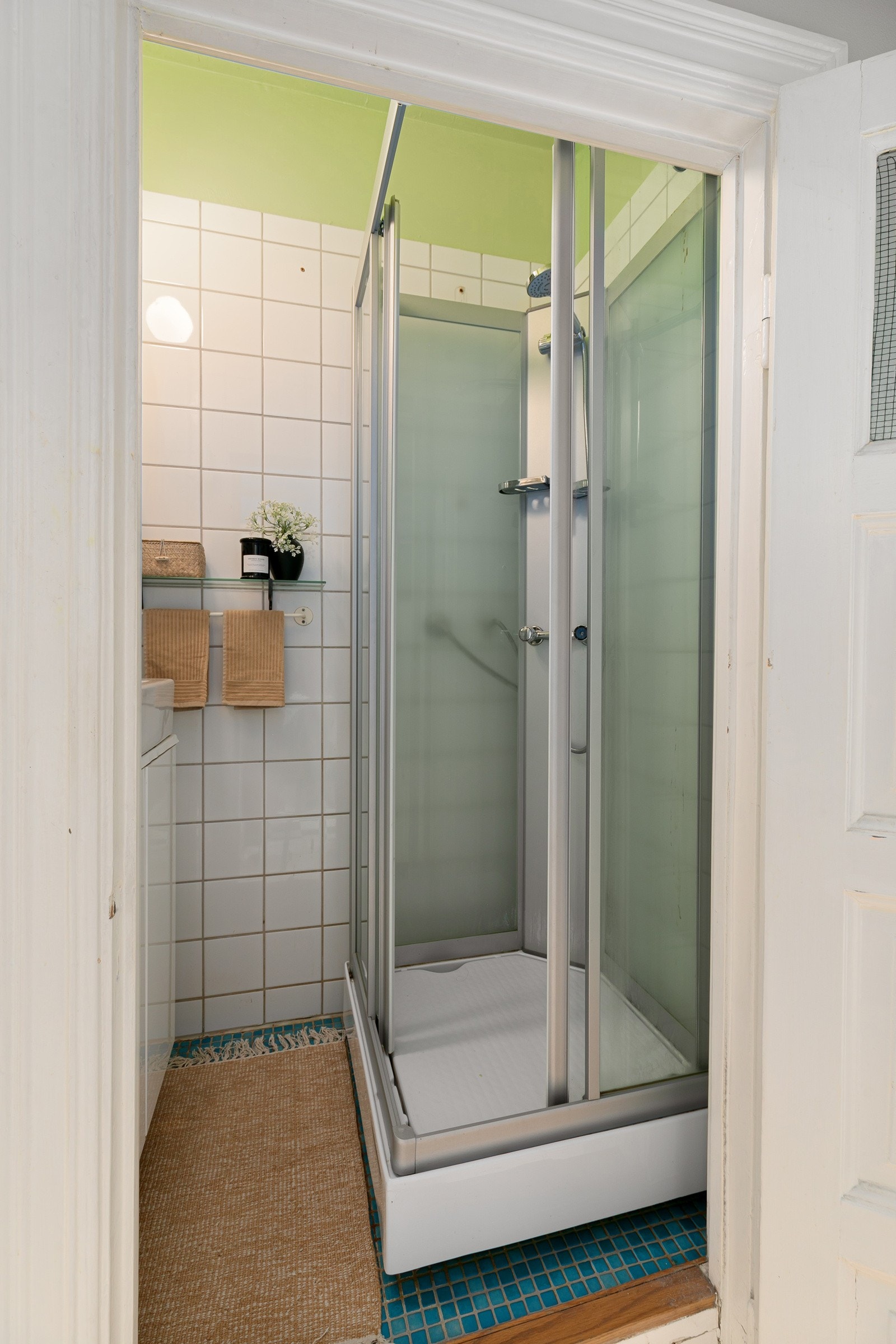 Flislagt dusjbad med servantskap, speil over servanten og dusjkabinett med skyvedør. Galleribilde